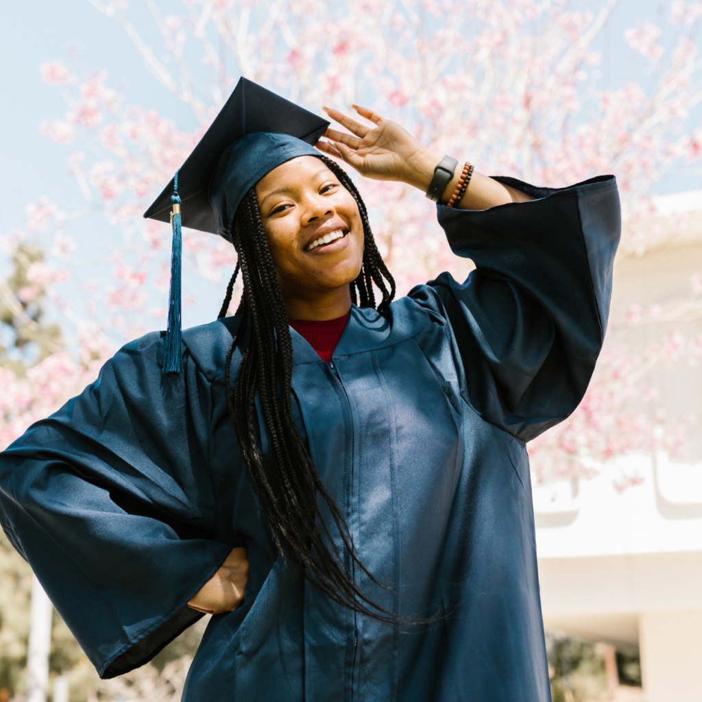 Smiling student in graduation gown striking a pose